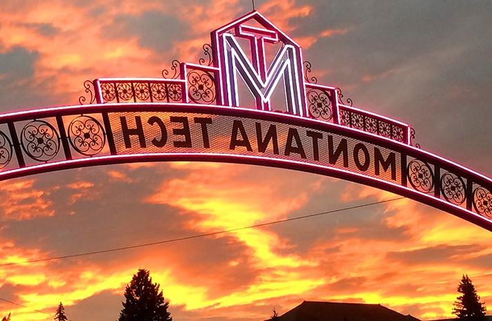 Archway that says "Montana Tech" with a sunset behind it